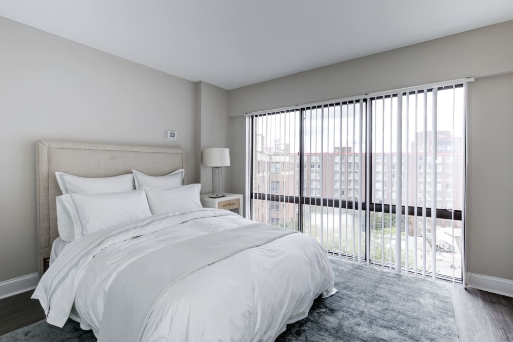 Gorgeous bedroom with all white decor and huge windows at The Cambridge Apartments in Washington, District of Columbia