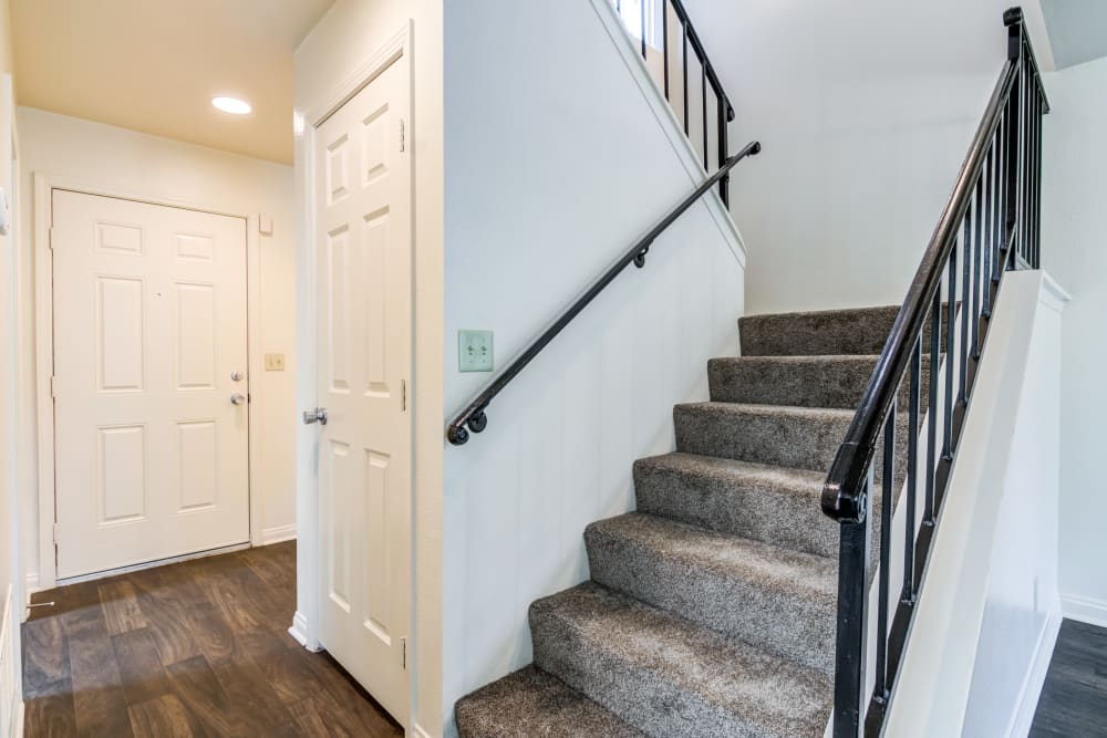 Hallway with wood flooring and carpeted staircase in a home at O'Neill Heights East in Oceanside, California
