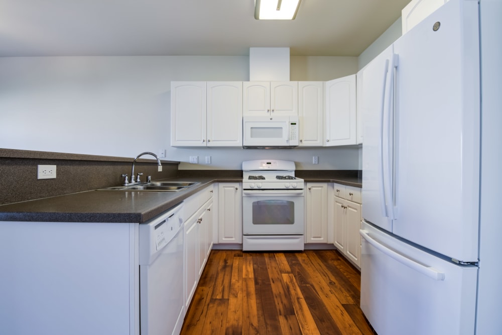 A fully-equipped kitchen with white cabinets at Harborview in Oceanside, California