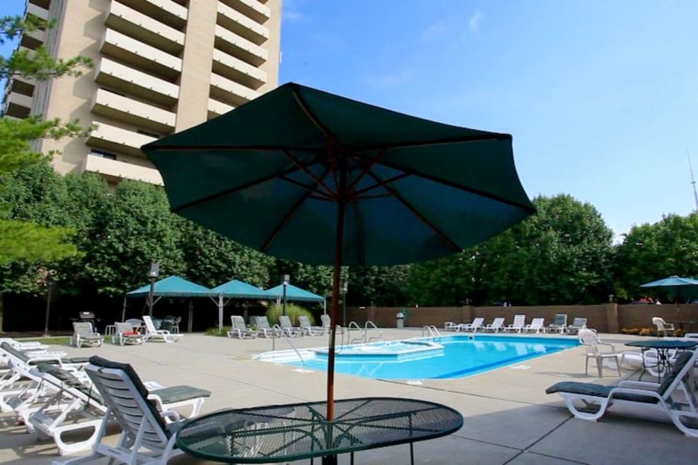 Swimming pool surrounded by lounge chairs and tables with umbrellas at The Canterbury in Columbus, Ohio