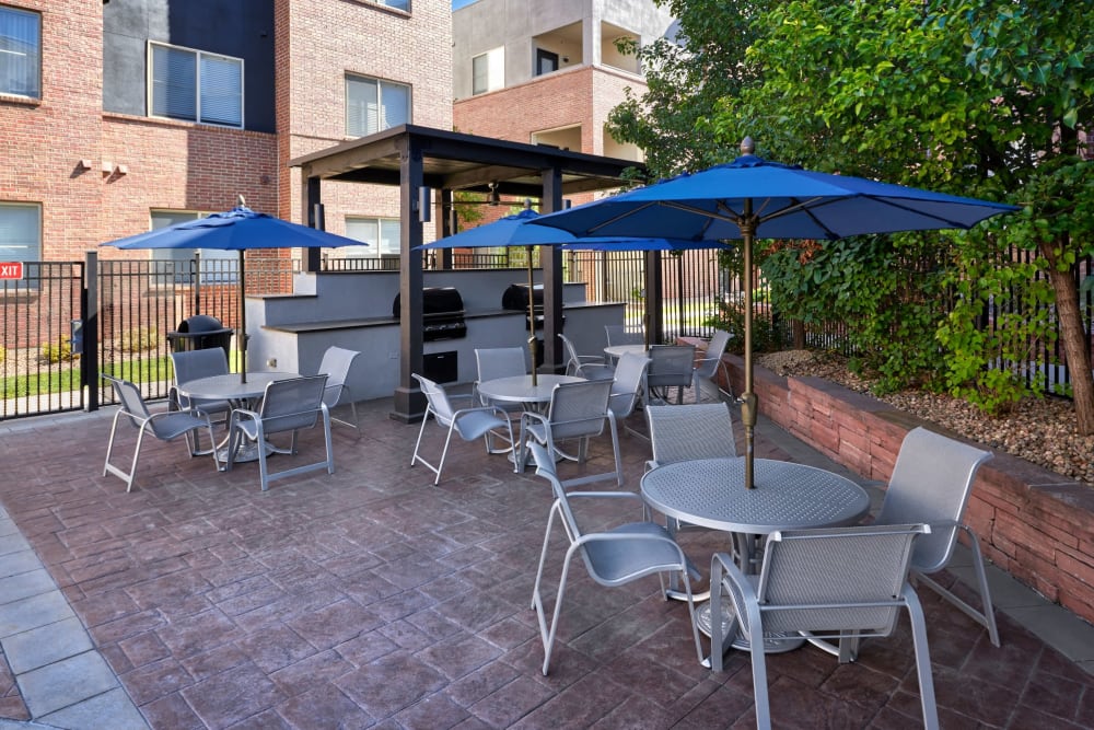 Grilling area with multiple tables and chairs that are covered to get out of the sun and enjoy your food by the pool at Marq Inverness in Englewood, Colorado