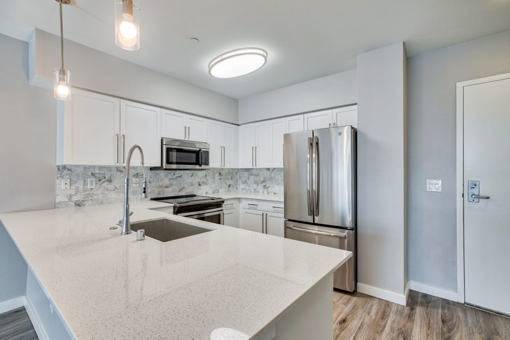 Quartz countertops and pending lighting in a model home's kitchen at 700 Broadway in Seattle, Washington