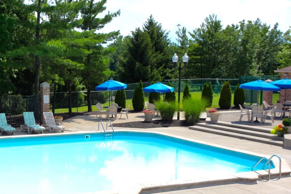 Swimming pool with lounge chairs and poolside patio tables and umbrellas at Parkhill Luxury Apartments in Columbus, Ohio
