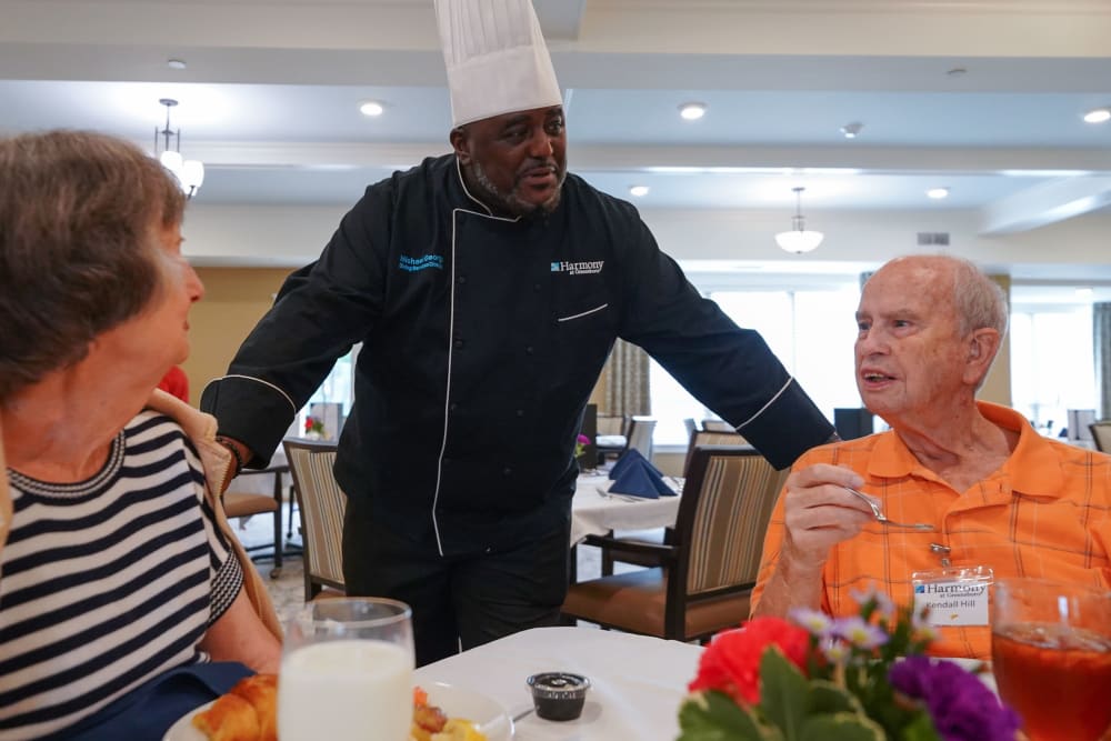 Chef with residents in dining room Harmony at Harbour View in Suffolk, Virginia