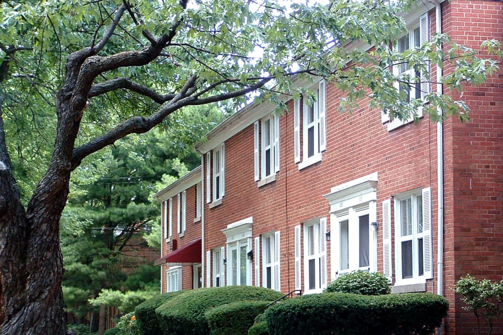 Brick building exterior and lush grounds with mature trees at Bexley Plaza in Columbus, Ohio