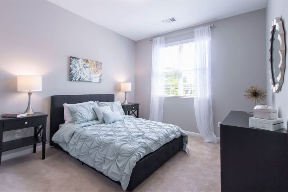 Well-furnished model home's primary bedroom with plush carpeting at Eagle Rock Apartments at Fishkill in Fishkill, New York