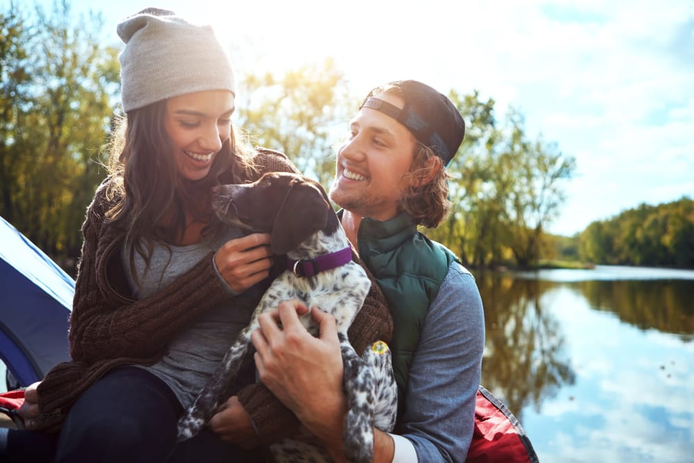 Cute couple outdoors by a lake with their puppy at Oswego Cove in Lake Oswego, Oregon