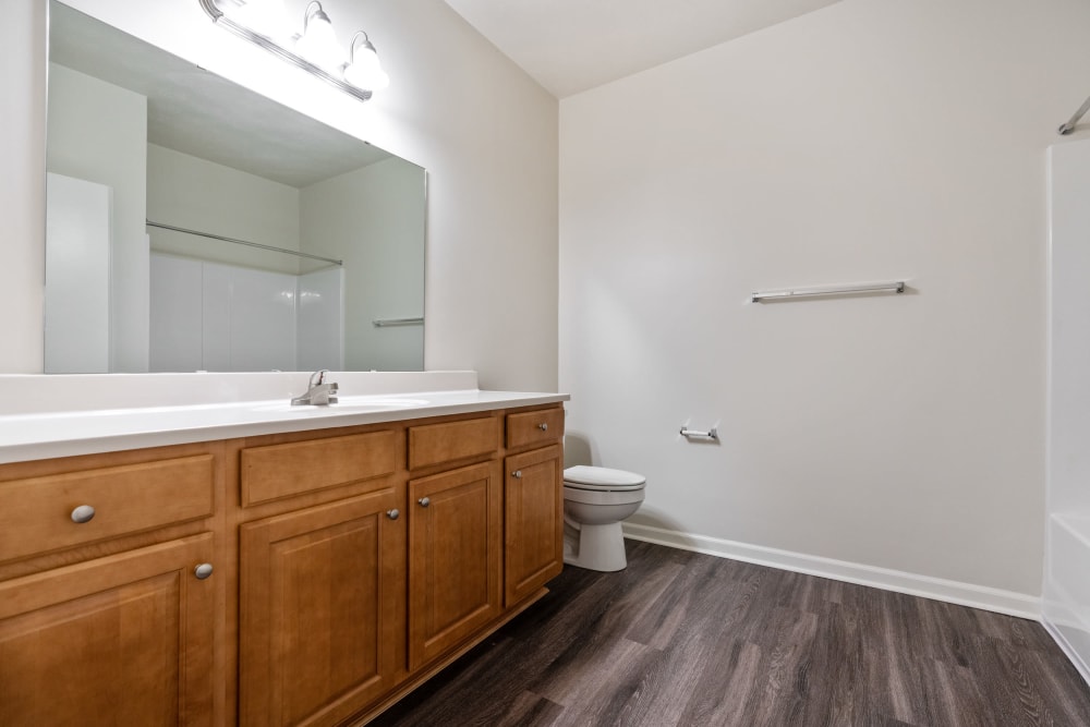 Model bathroom with plank flooring at Cane Run Station Apartments in Louisville, Kentucky