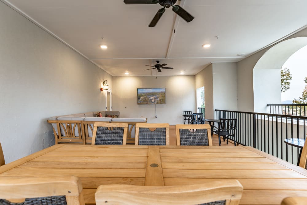 Covered outdoor deck with wooden tables and a tv at The Blake at Charlottesville in Charlottesville, Virginia