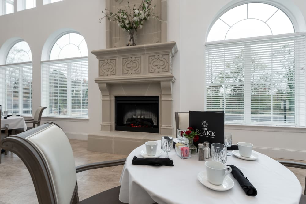 Ornate fireplace mantle by a round dining table set for 4 at The Blake at Charlottesville in Charlottesville, Virginia