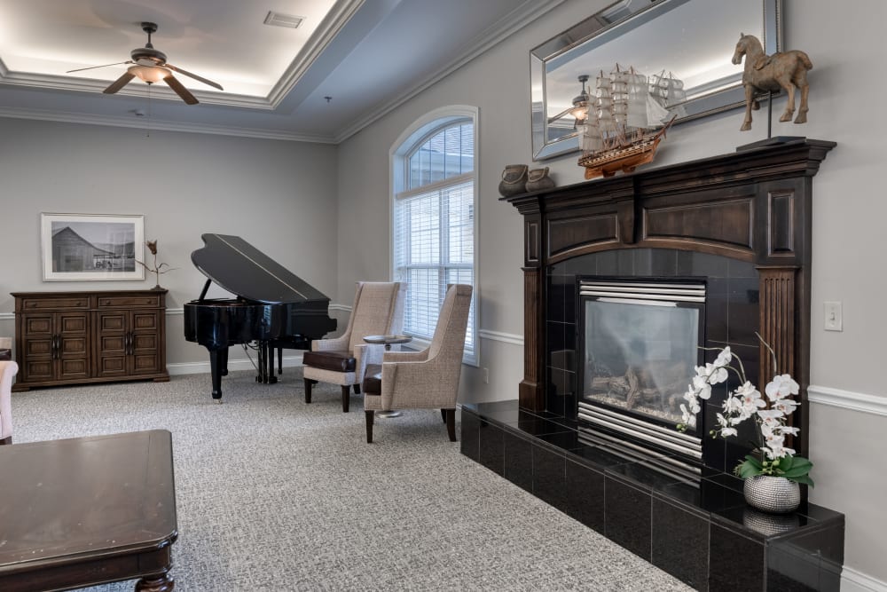 Lounge with a grand piano and a fireplace at Addington Place of Shoal Creek in Kansas City, Missouri