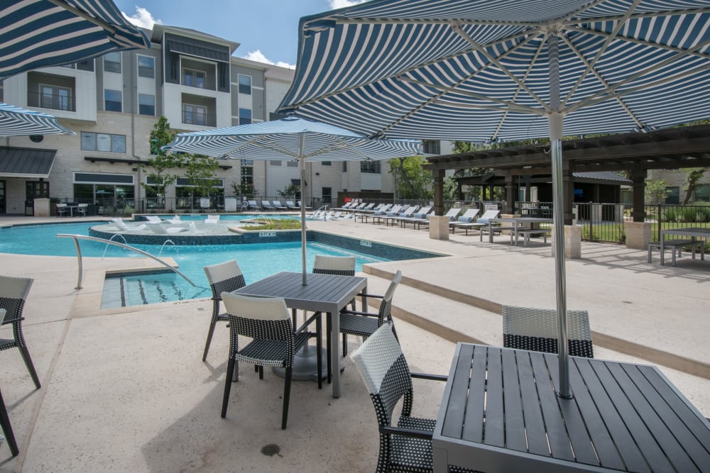 Tables with umbrellas by the pool for residents at Marquis Dominion in San Antonio, Texas