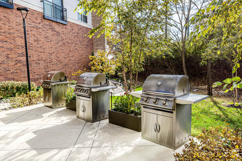 Clayton, MO Apartments - The Barton - Poolside BBQ Area with Grills and Beautiful Landscaping