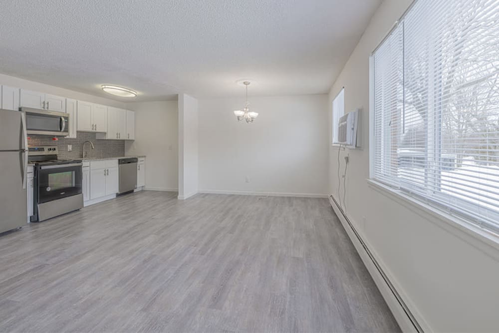 Spacious living area and open modern kitchen with luxury plank flooring at Creek Hill Apartments in Webster, New York