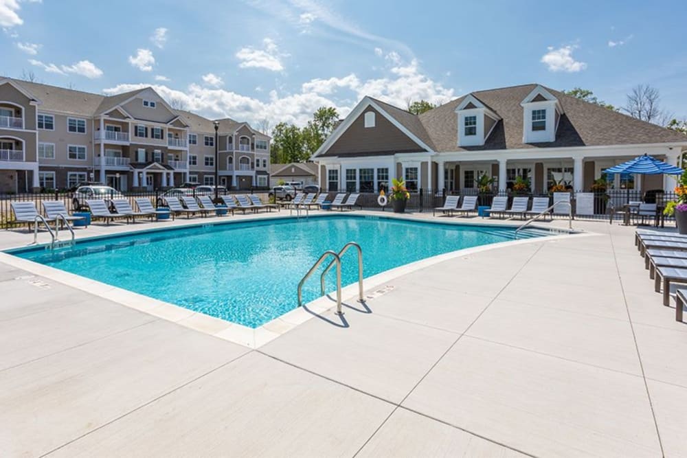 Luxurious pool with lounge chairs on the sides of it at Winding Creek Apartments in Webster, New York