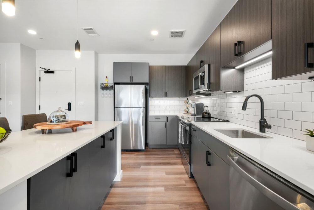 Hardwood-style flooring and quartz countertops in a model apartment's kitchen at Anden in Weymouth, Massachusetts