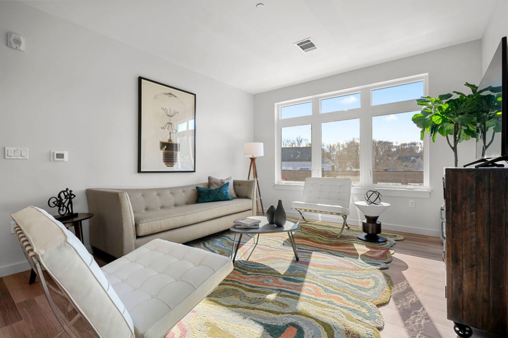 Bay windows and modern furnishings in a model apartment's living space at Anden in Weymouth, Massachusetts