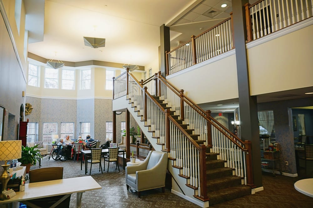 Dining hall with stairs to the second floor at Addington Place of Collinsville in Collinsville, Illinois