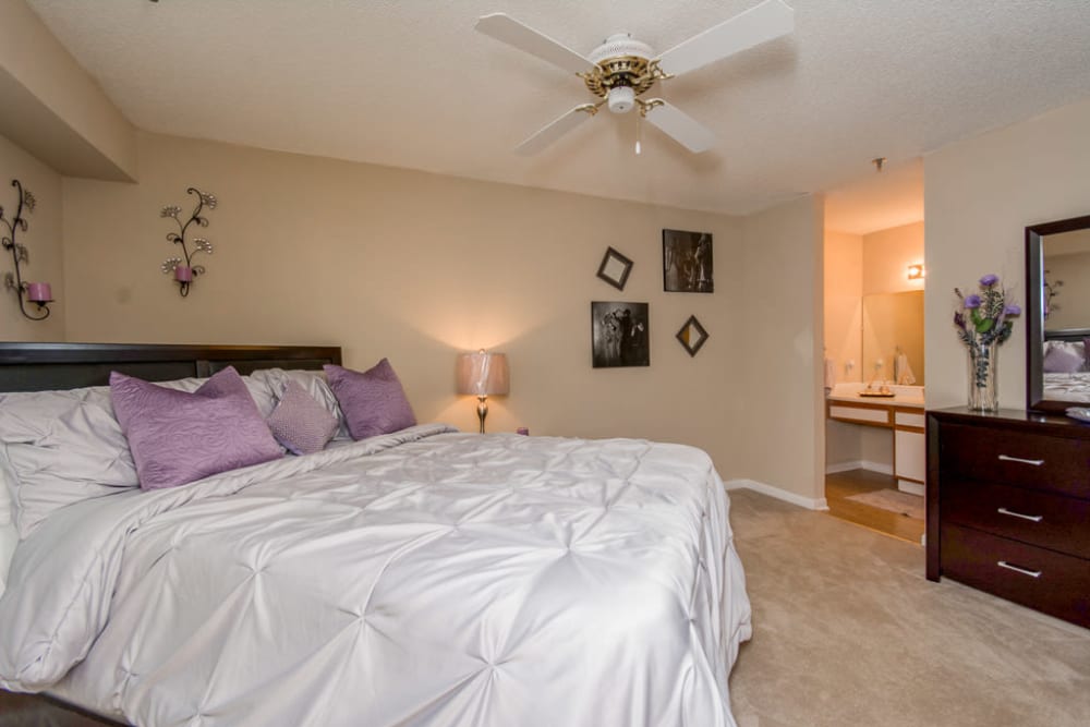 Large bed and celling fan in the bedroom of a model home at Arbor Crossing Apartments in Lithonia, Georgia