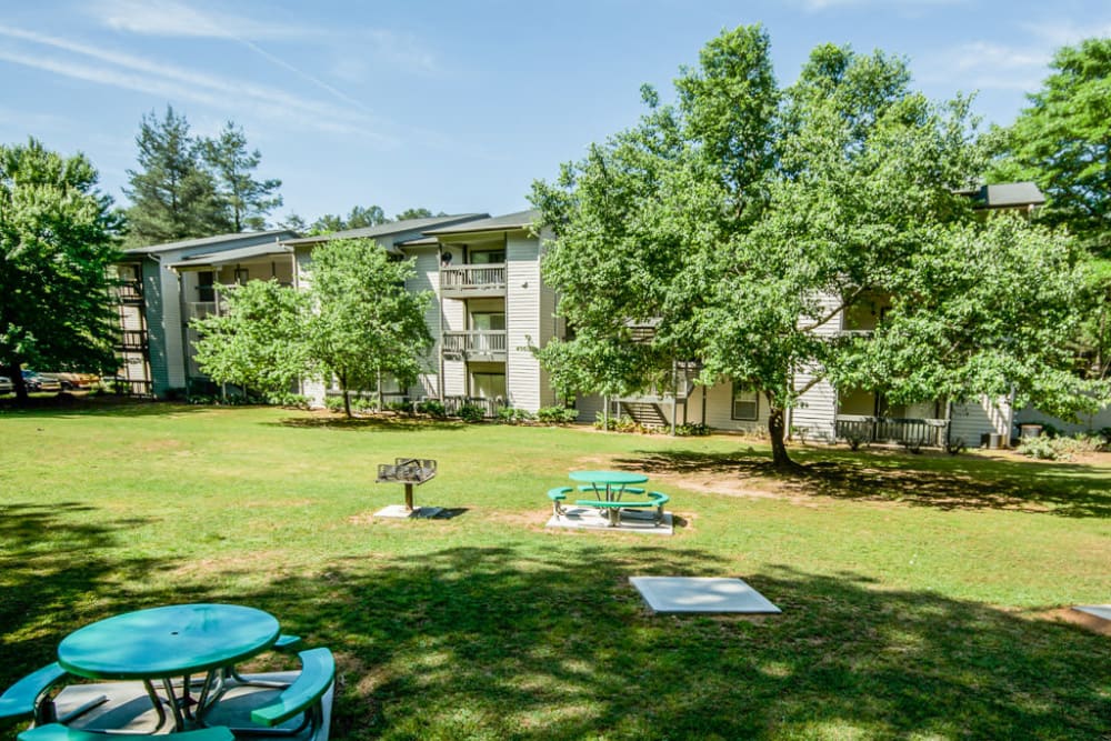 Grilling area outside on the grass with tables around it to eat on at Arbor Crossing Apartments in Lithonia, Georgia