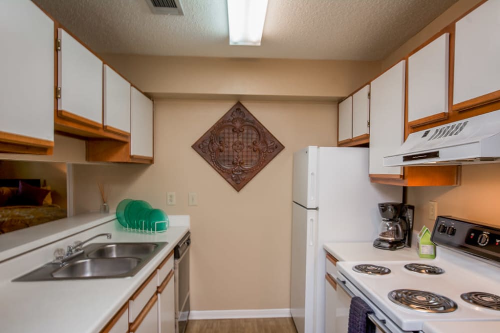 Nice kitchen with white cabinets that have a light wood style trim at Arbor Crossing Apartments in Lithonia, Georgia