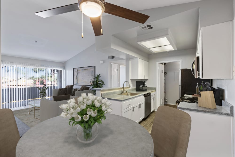 A dining room with views into the living room and ktchen with white cabinets at Sierra Del Oro Apartments in Corona, California