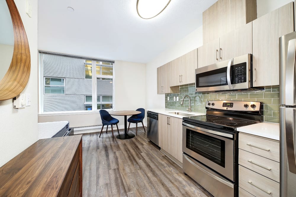 Large kitchen and dining area with sleek wood style flooring at Alley South Lake Union in Seattle, Washington