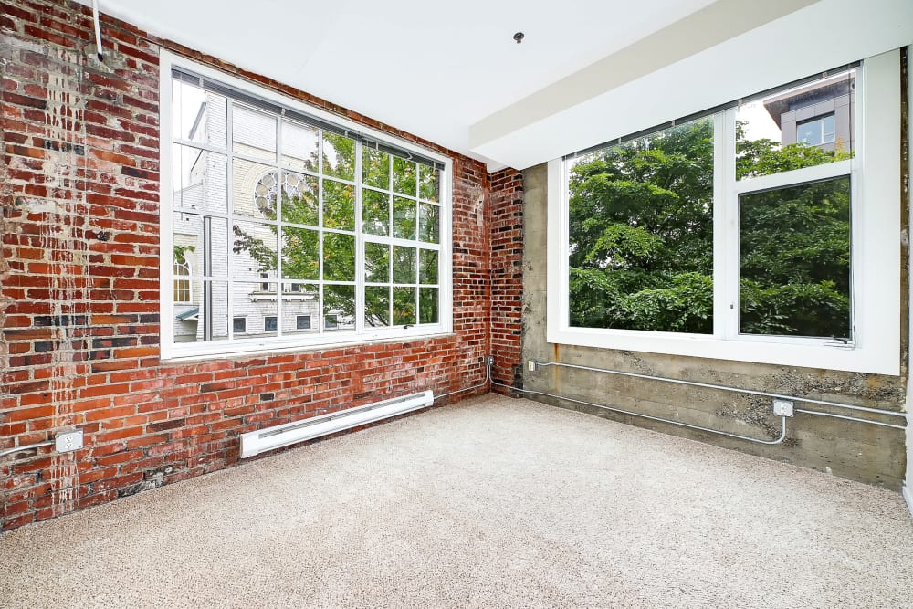Spacious living area with one brick style wall and large windows at Alley South Lake Union in Seattle, Washington