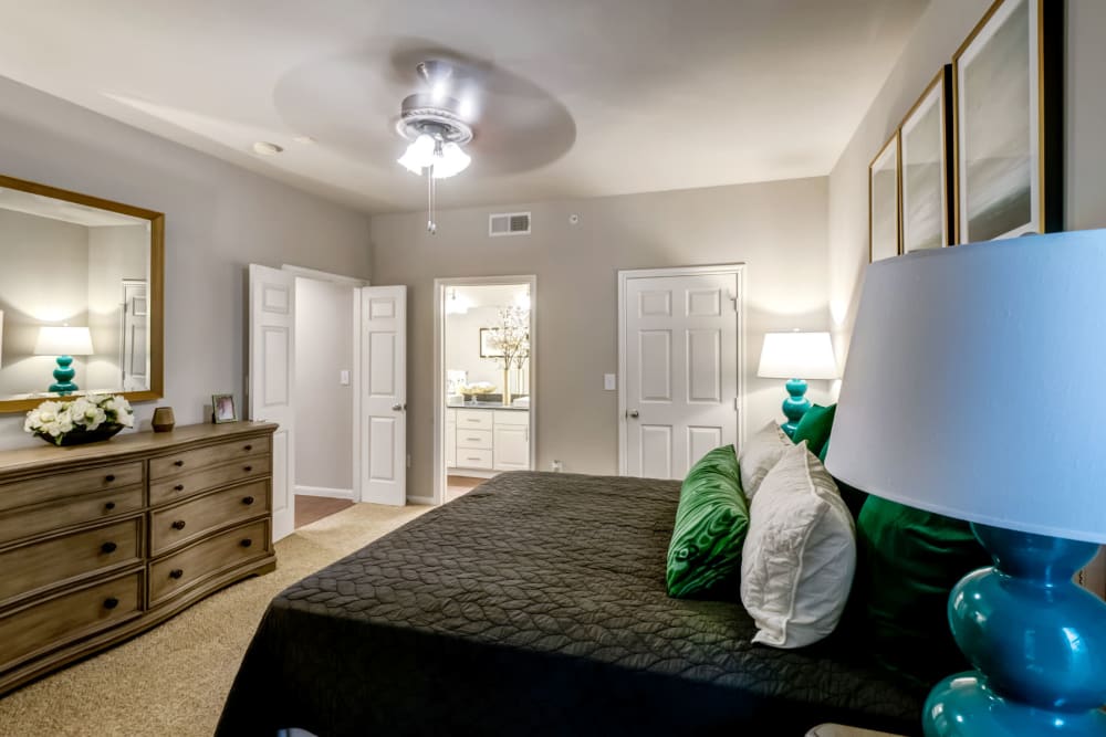 Spacious primary suite with a ceiling fan and plush carpeting in a model home at Sonterra Heights in San Antonio, Texas