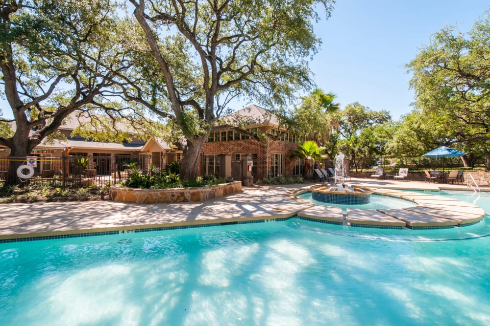 Mature trees partially shading the swimming pool and spa with a fountain at Sonterra Heights in San Antonio, Texas