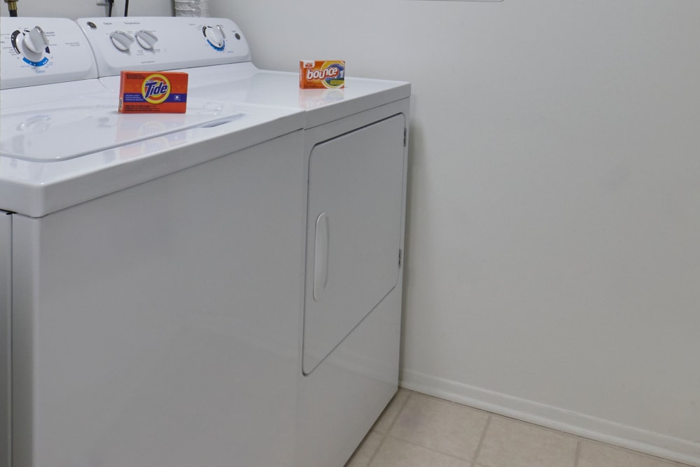 Full-size washer and dryer in a furnished suite at Farmington Oaks Apartments in Farmington, Michigan