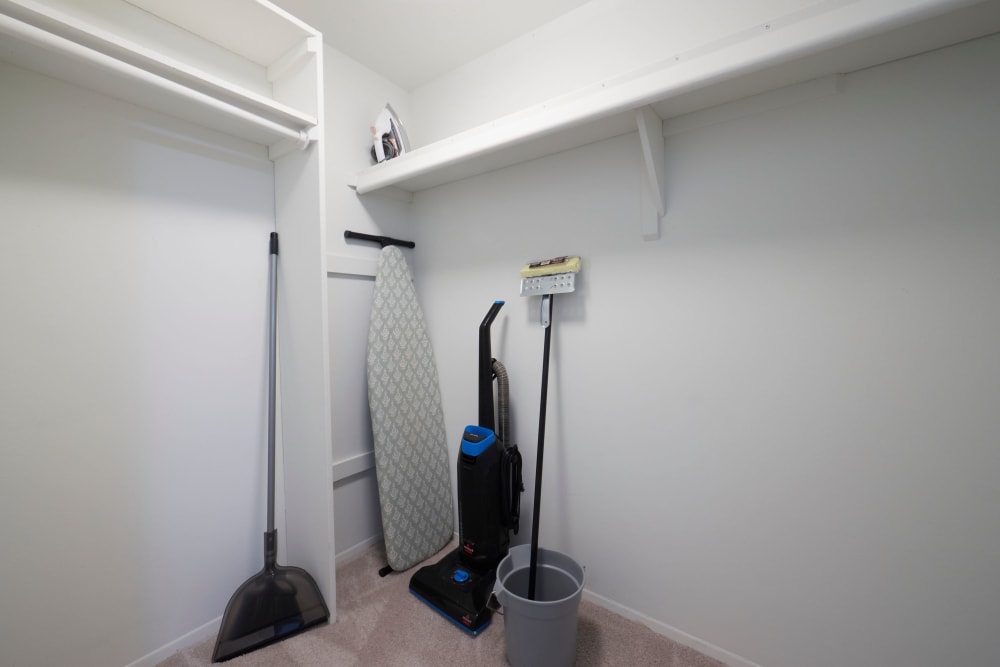 Walk-in closet with cleaning supplies at Kensington Manor Apartments in Farmington, Michigan