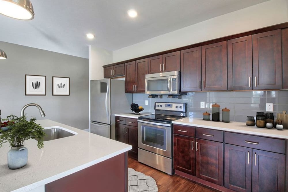 Rich espresso wood cabinetry and stainless-steel appliances in a model apartment's kitchen at Pinnacle North Apartments in Canandaigua, New York