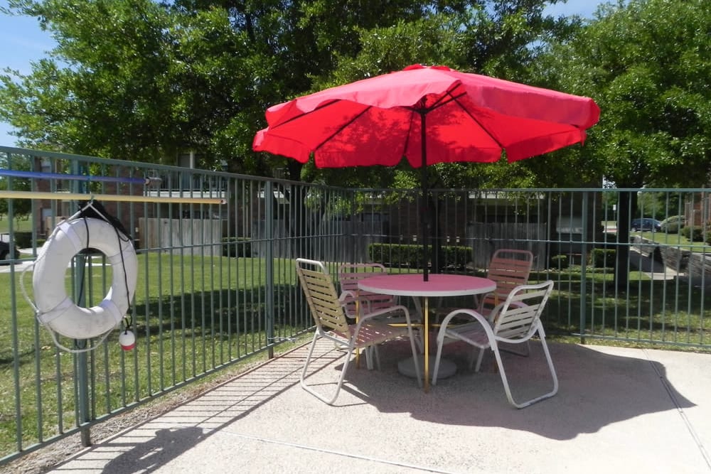 Poolside picnic table with umbrella at Summit Point Apartments in Mesquite, Texas