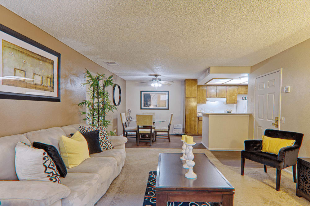 Furnished living room with large sofa with black and yellow pillows at Cordova Park Apartments in Lancaster, California