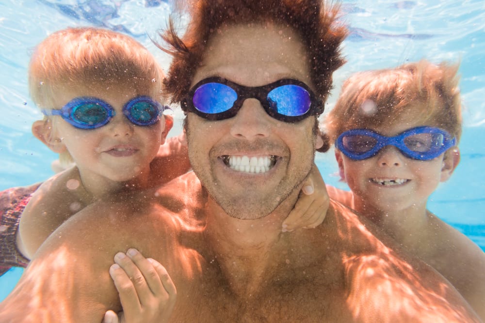 a dad with his kids underwater swimming at Park Hills Apartments in Cleveland, Tennessee