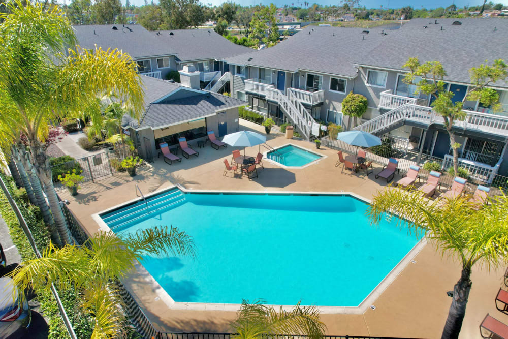 Beautiful resort-style swimming pool with lounge chairs and umbrellas at Hillside Terrace Apartments in Lemon Grove, California