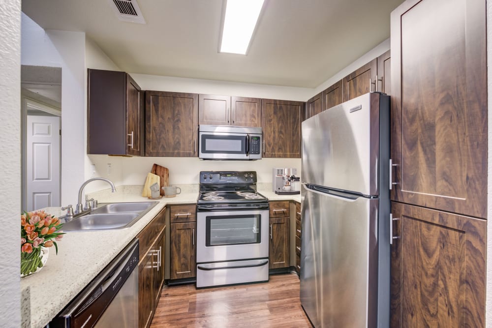 Open kitchen and dining with wood-style flooring at Tuscany Village Apartments in Ontario, California