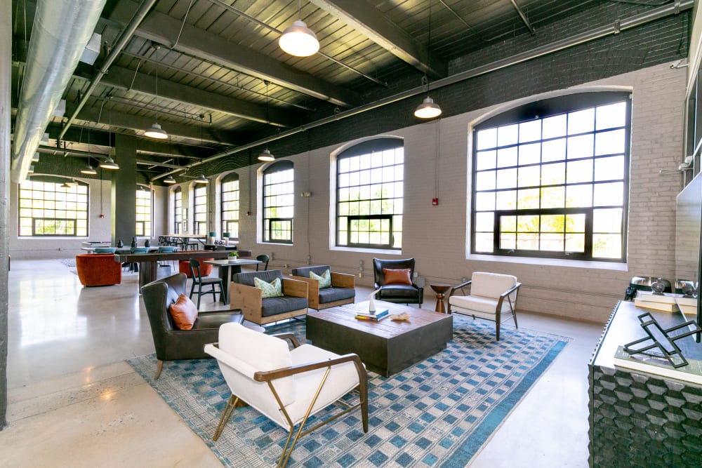 Open floor plan community space with large windows for ample natural light, couch seating and tables at Lofts at Riverwalk in Columbus, Georgia