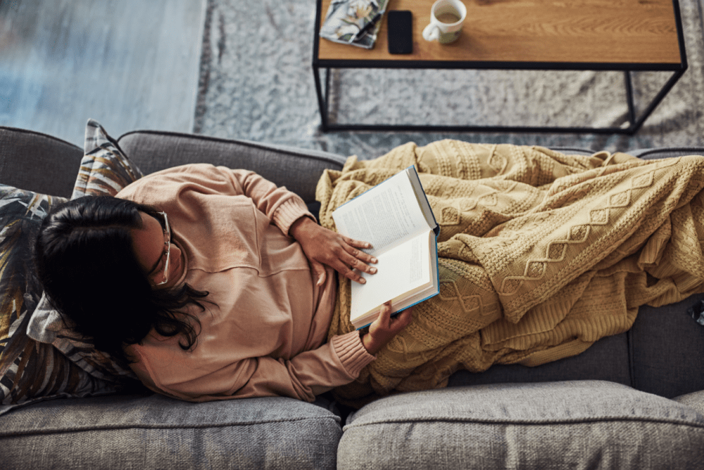 Woman reading a book while laying on the couch at Woodspring Apartments in Tigard, Oregon