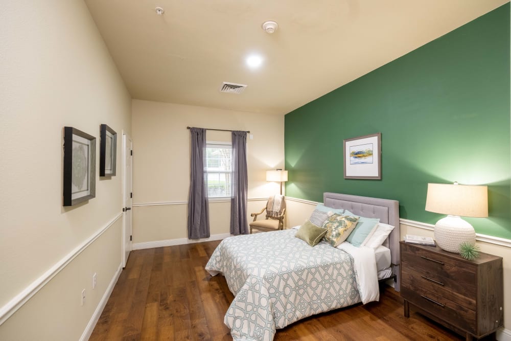 Bedroom with green accent wall at The Heritage Memory Care in The Woodlands, Texas