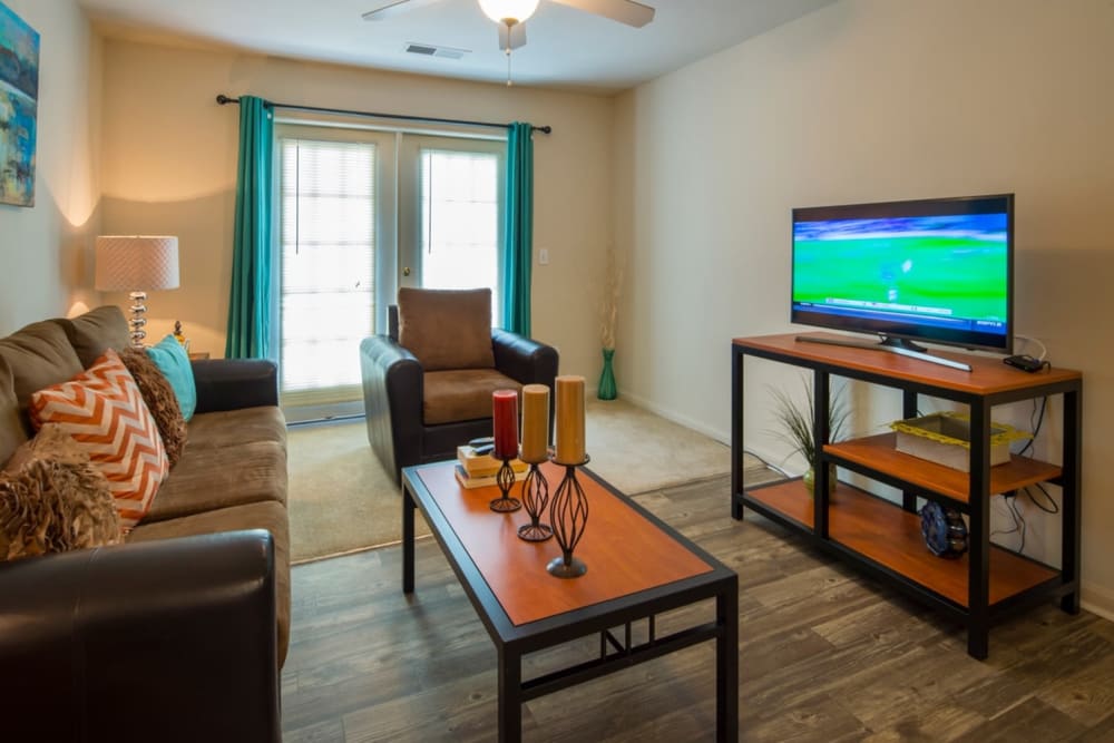 Spacious model living room with hardwood style flooring at Campus Crossings in Murfreesboro, Tennessee