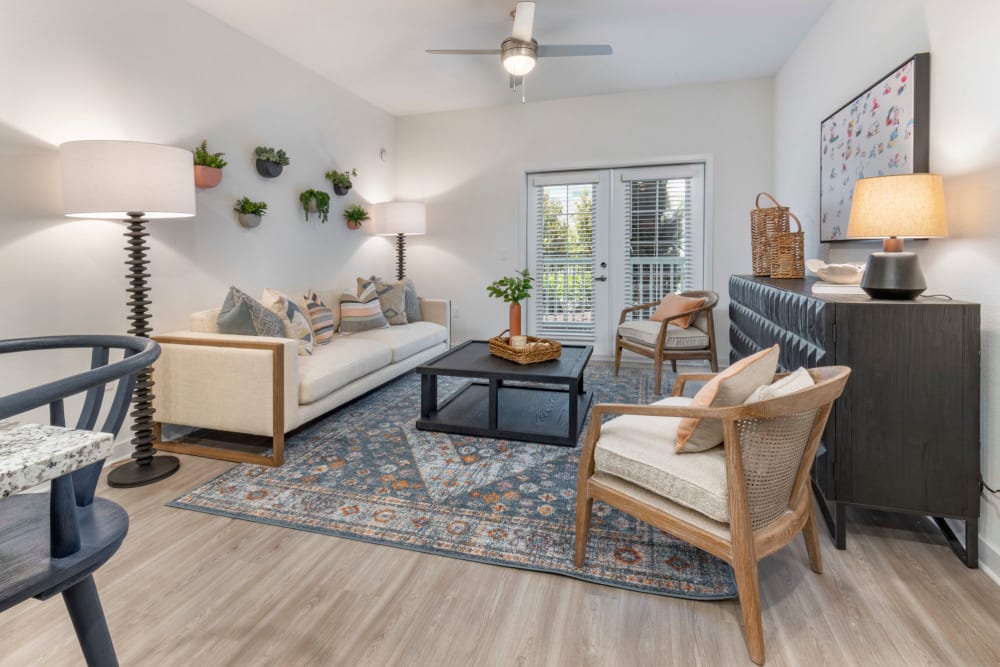 Apartments in Lutz for Rent - Sage at Cypress - Living Room With  a Ceiling Fan, White Couch, Vinyl Flooring, and Two Doors Leading to Balcony/Patio
