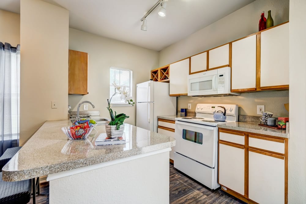 Beautiful modern kitchen with white appliances and a table at Legacy of Cedar Hill Apartments & Townhomes in Cedar Hill, Texas