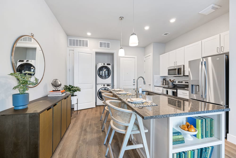 Apartment kitchen with white cabinets and stainless steel appliances and full sized washer and dryer at The Avery in Austin, Texas