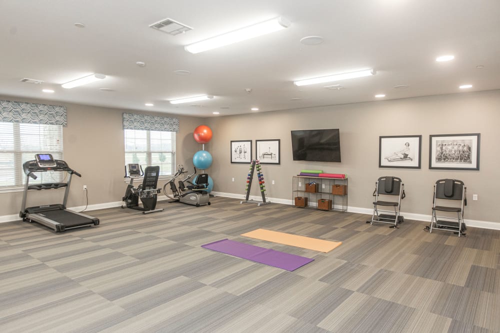 Exercise room with a wall mounted TV at The Princeton Senior Living in Lee's Summit, Missouri