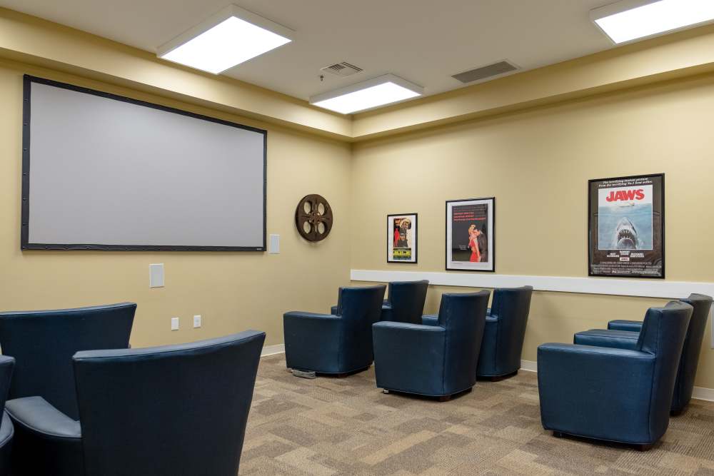  Community theatre with a projector and multiple seating at The Harmony Collection at Roanoke - Memory Care in Roanoke, Virginia