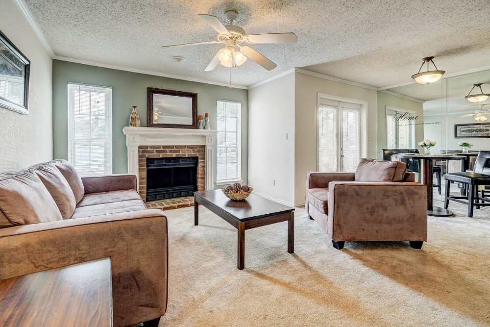 Well lit Carpeted living room connecting Dining room with couch, coffee table and fireplace at Peppertree Apartment Homes in Lafayette, Louisiana