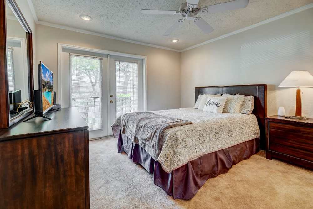 Well-lit bedroom with large window, plush carpet, Desk and ceiling fan at Peppertree Apartment Homes in Lafayette, Louisiana