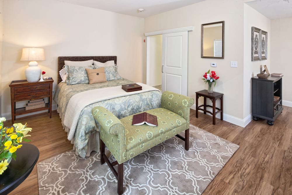 An apartment bedroom with wood-look flooring at The Village of Meyerland in Houston, Texas